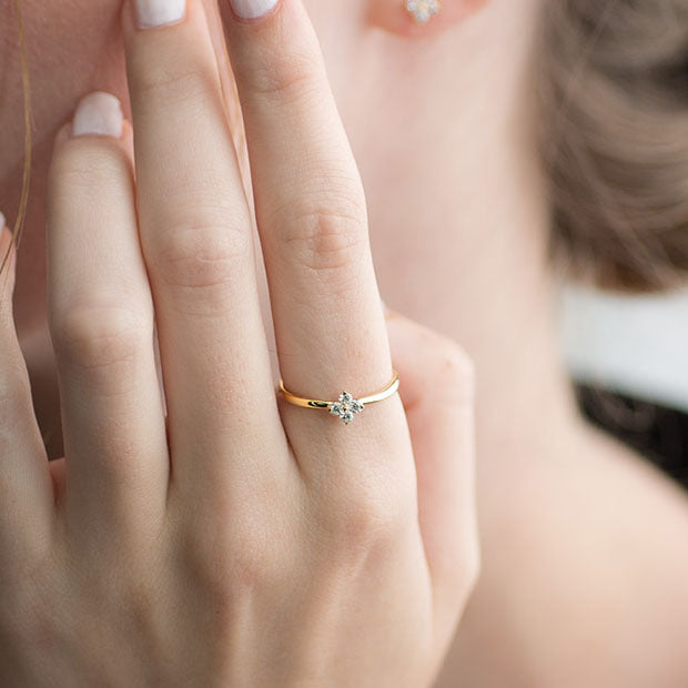 Close-up of a lucky four-leaf clover ring being modeled. Crafted from 14k gold-plated sterling silver and paved with sparkling diamonds, it serves as an ideal gift.